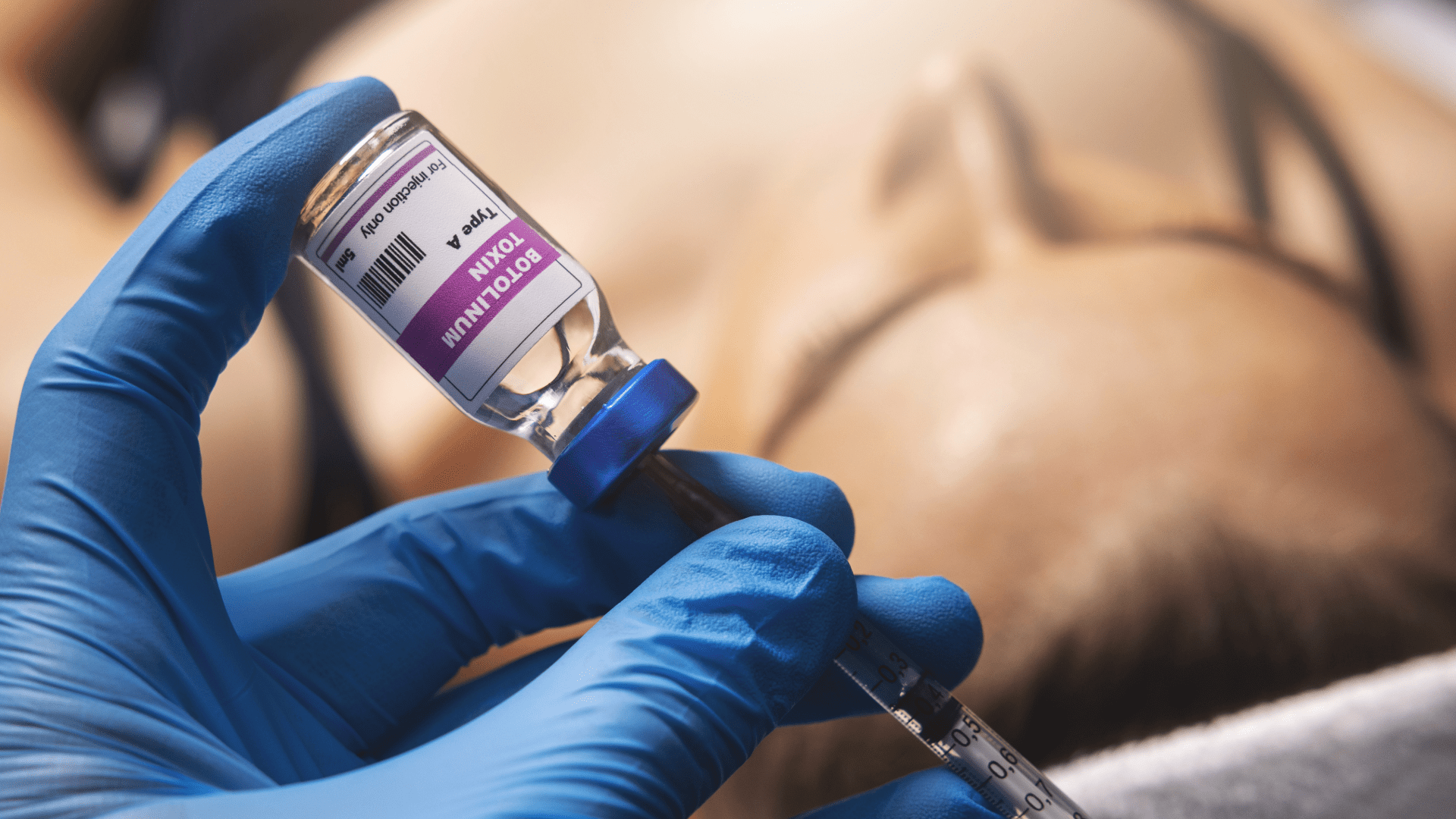Medical professional in blue gloves draws a botulinum Type A vial for injection into a patient. The label reads Botulinum Type A.