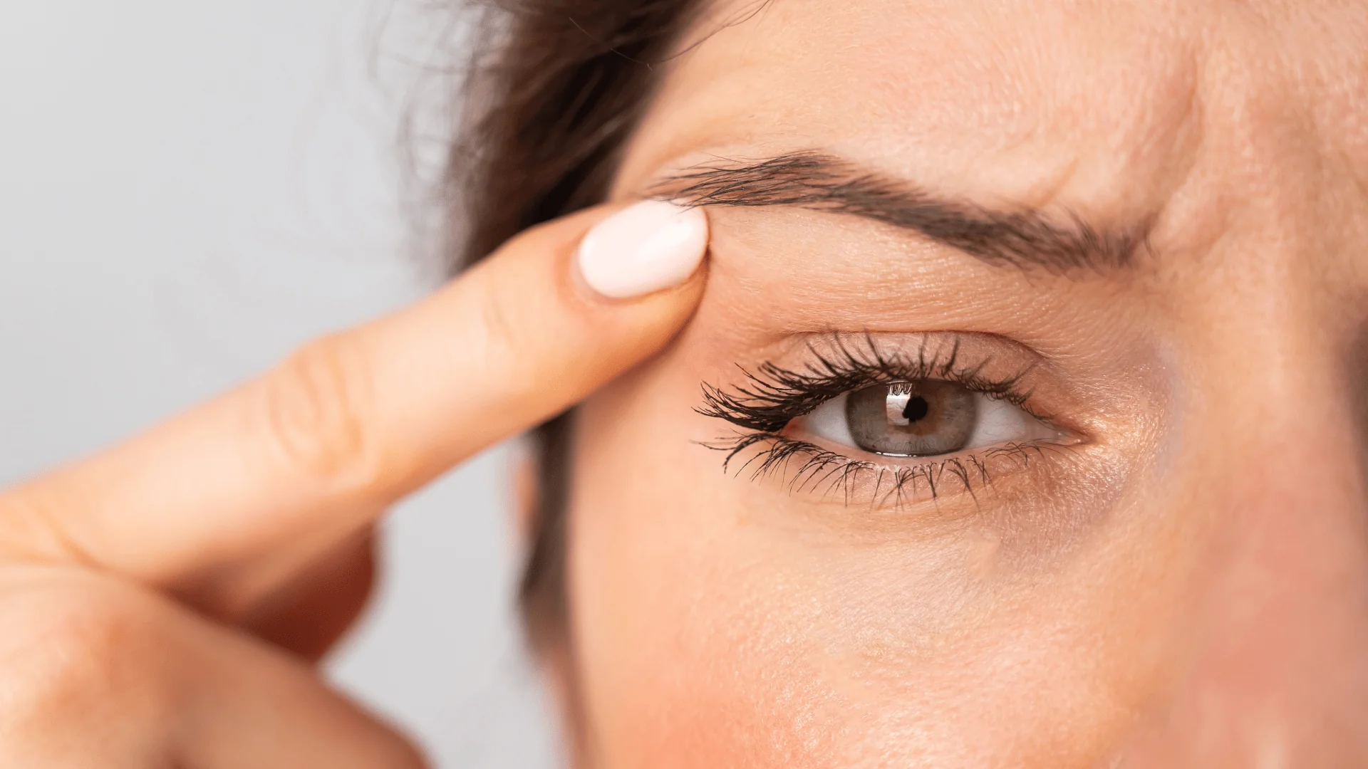 Unbenannt-1-31 - Dr. Pumberger Close-up of a person pulling down the lower eyelid to reveal a green eye with visible lashes and skin texture
