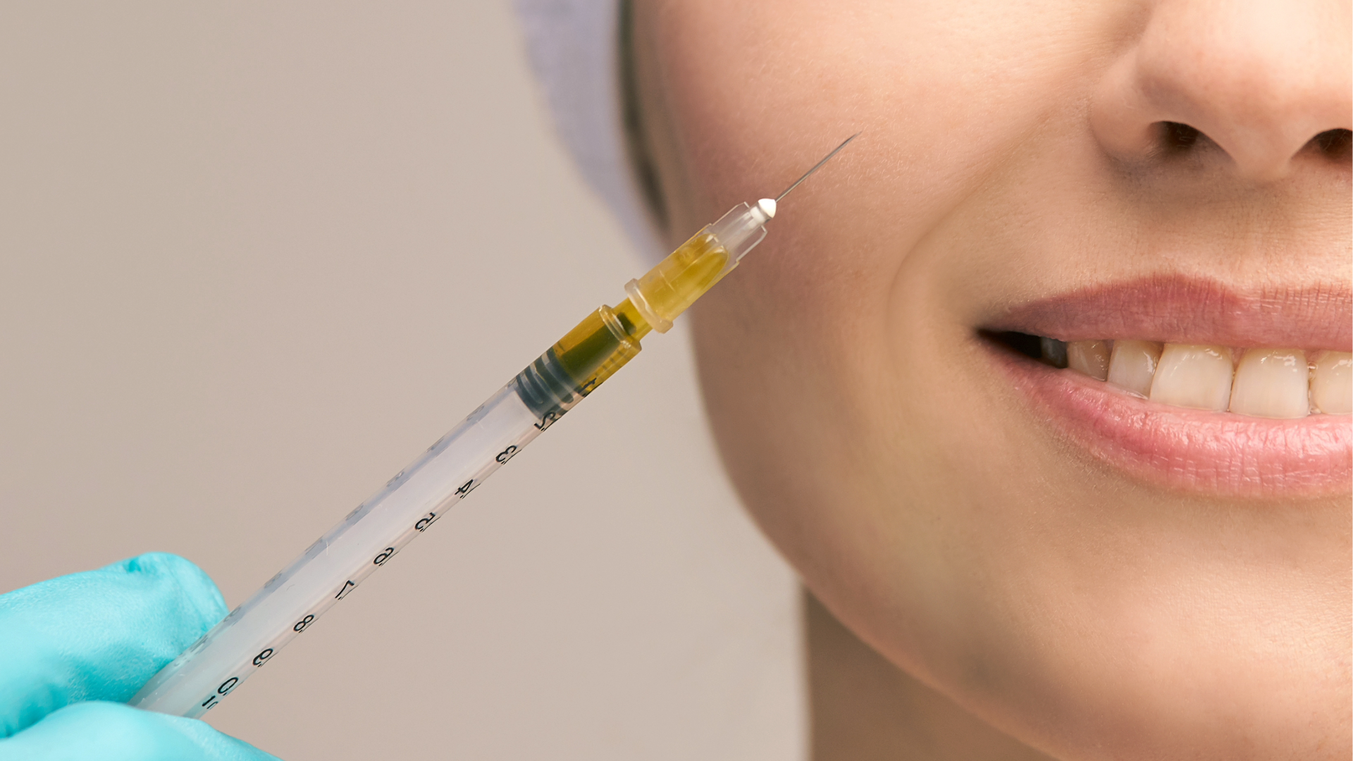 Close-up of a syringe with a yellow liquid near a person's cheek, about to administer an injection.