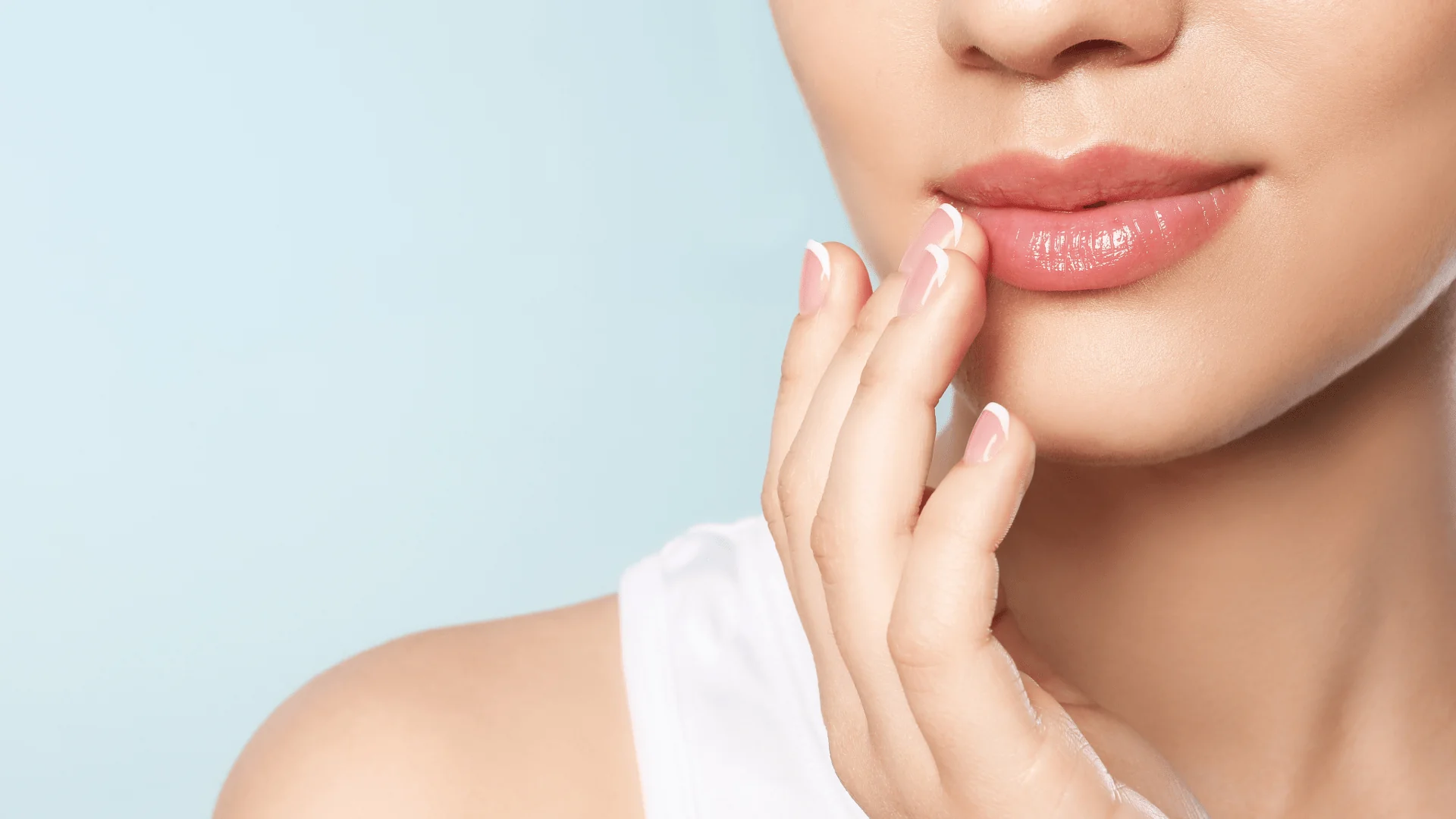 Unbenannt-47 - Dr. Pumberger Close-up of glossy pink lips being touched by neatly manicured fingers against a pale blue background, conveying skincare/cosmetic care.